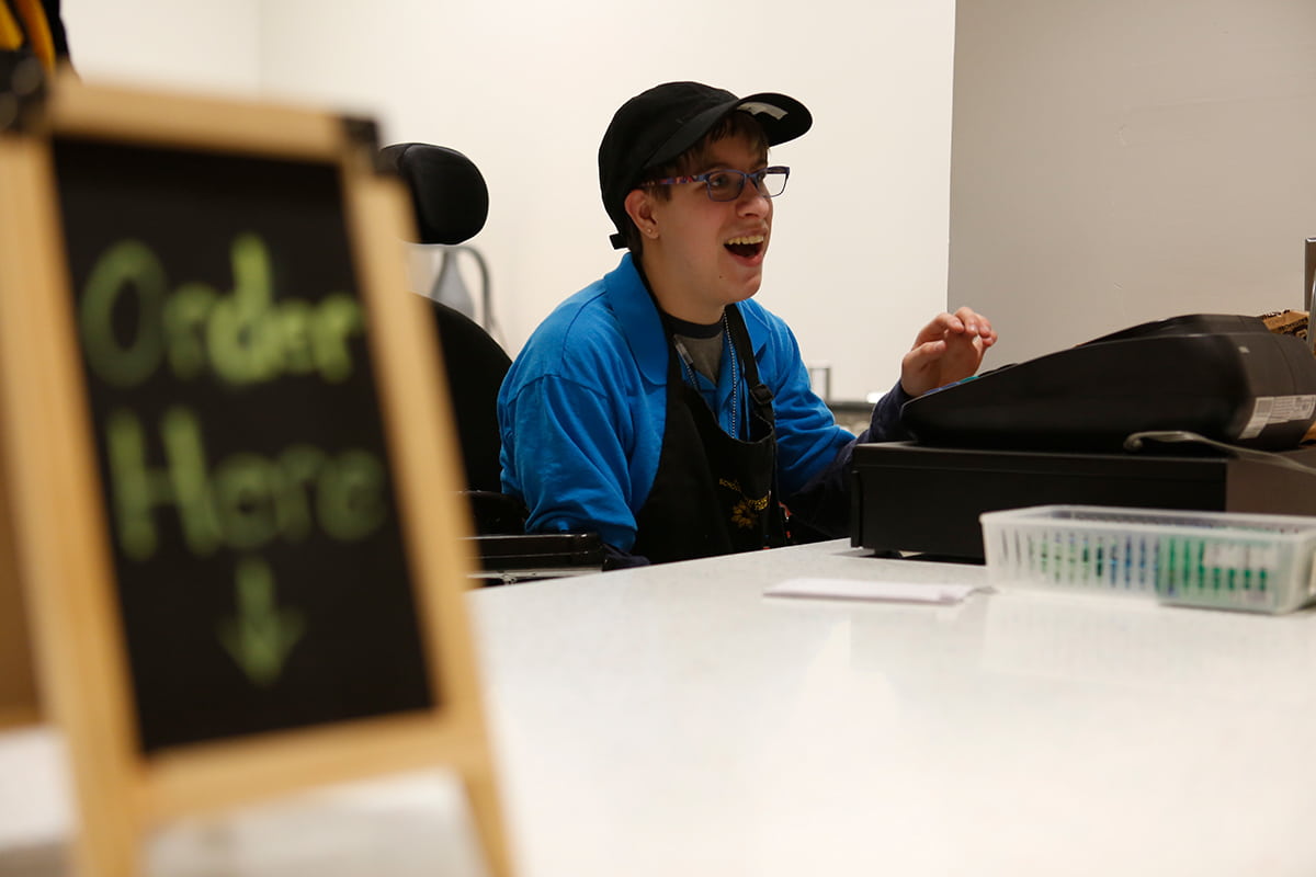 Sydney at register in cafe smiling