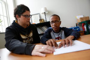Instructor ayudando a un alumno a leer en braille