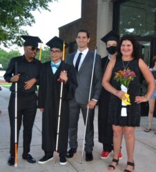 4 graduates pose with the commencement speaker