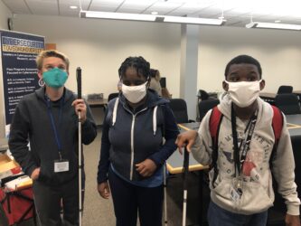 tres estudiantes con bastones que llevan máscaras
