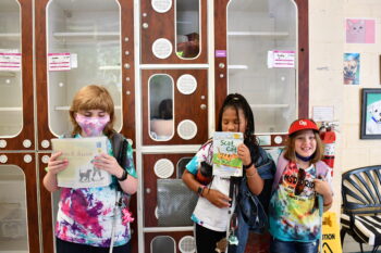 3 girls holding up books