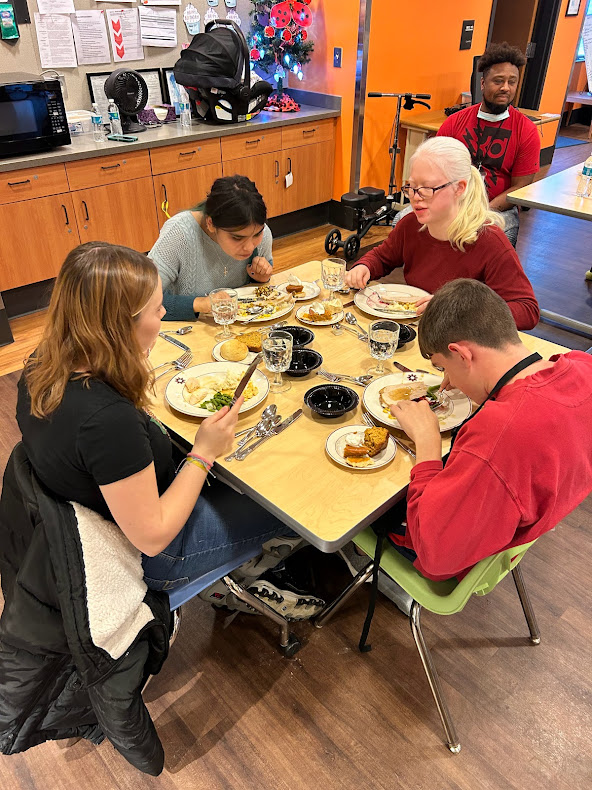 Four students practice cutlery skills while enjoying a Thanksgiving meal.