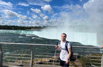 a man standing on the side of a bridge next to a waterfall.