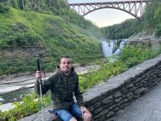 a man sitting on a stone wall holding skis.