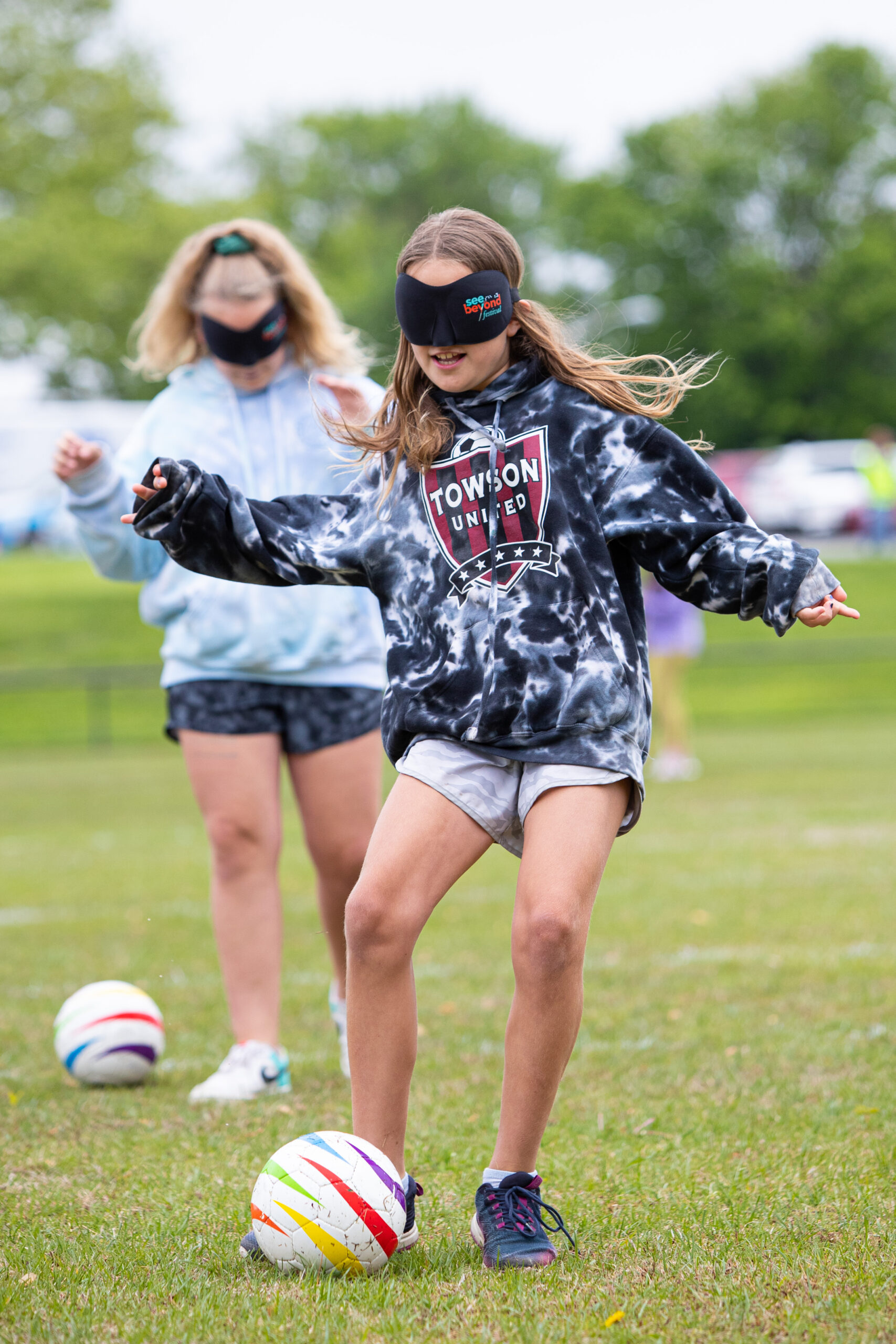 a young girl kicking a soccer ball on a field. a young girl kicking a soccer ball on a field.