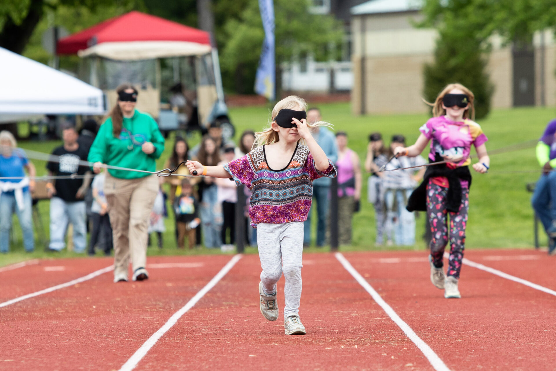 a group of people running on a track with blindfolds. a group of people running on a track with blindfolds.