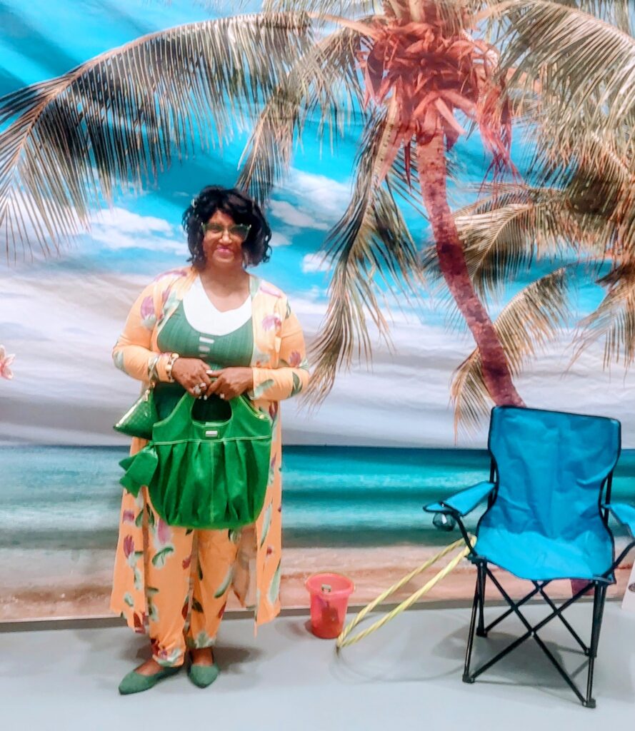 A woman standing in front of a palm tree with a green bag.
