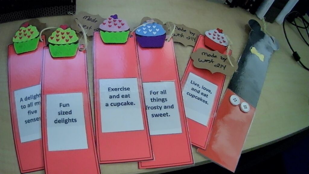 Handmade bookmarks with colorful cupcake designs and motivational phrases on a desk.