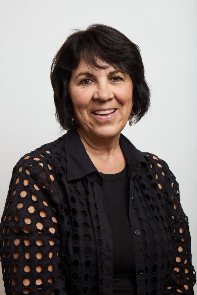 Smiling woman with short dark hair wearing a black textured top.