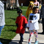 A group of people walking down a sidewalk.